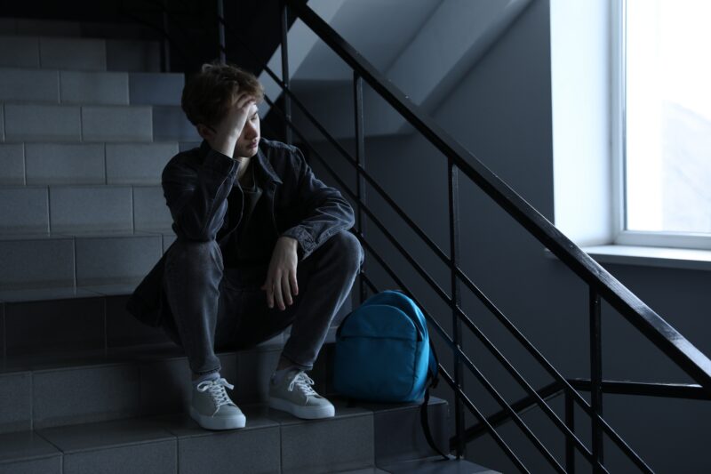 Student sitting on stairs in the hallway being upset and sad