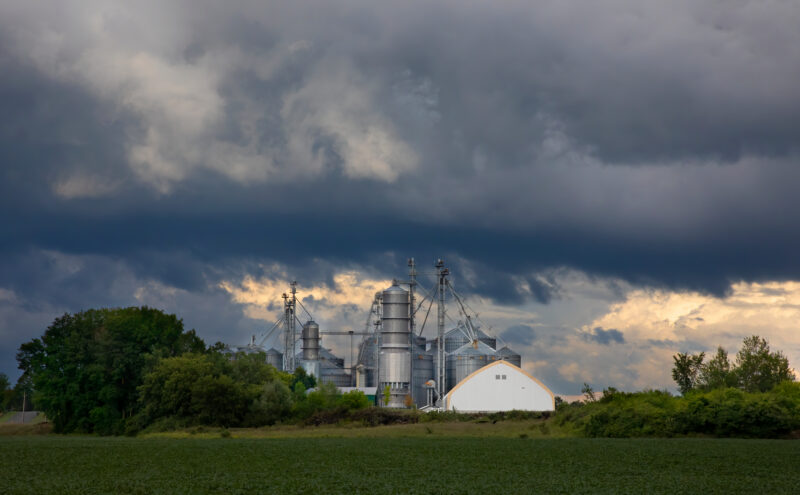 Industrial facility under severe convective storm clouds, illustrating property and insurance risk from extreme weather
